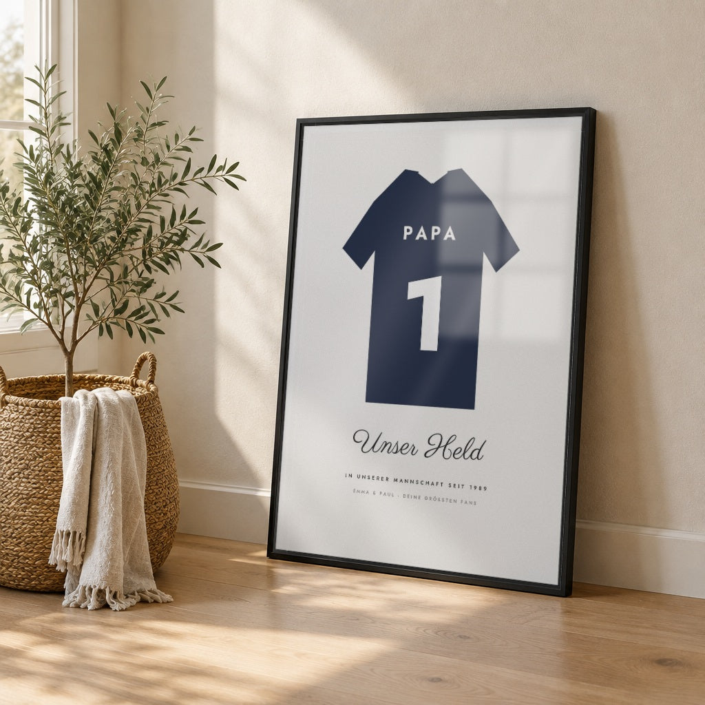 Trikotposter mit Name & Nummer – dein Trikot – im schwarzen Rahmen an die Wand gelehnt