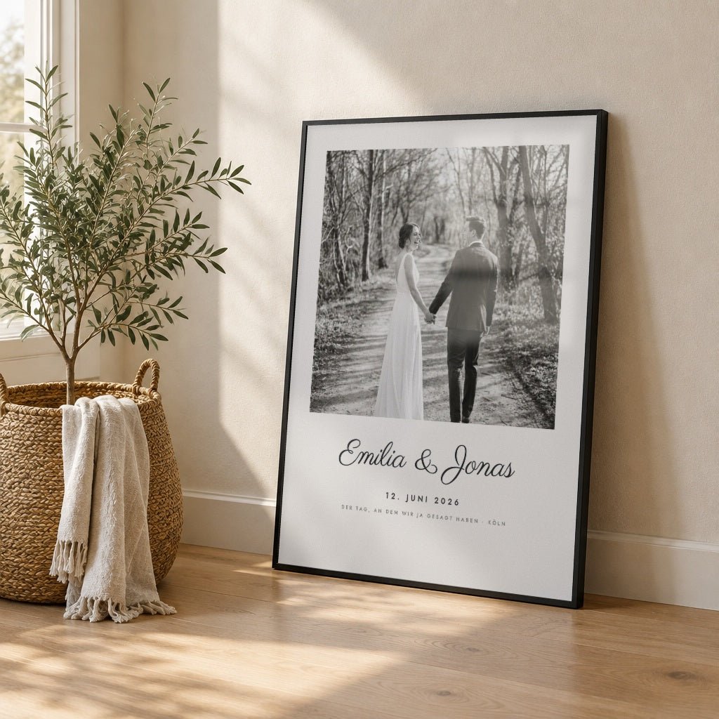 Hochzeitsposter mit Foto – euer Tag – im schwarzen Rahmen an die Wand gelehnt