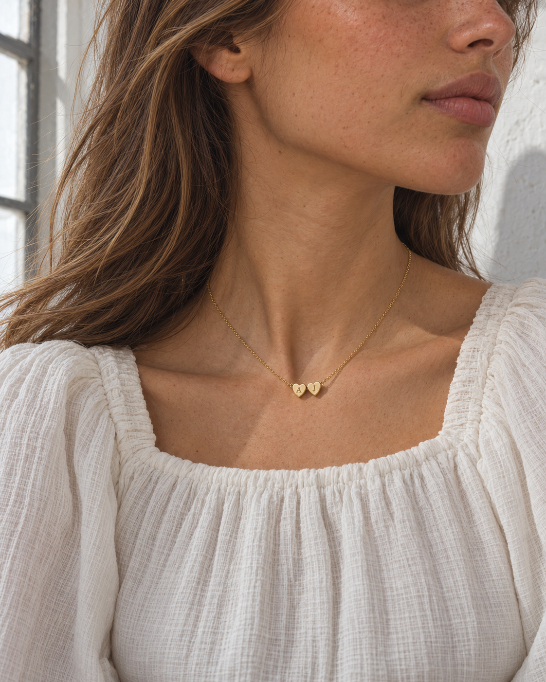 SONJA Kette mit zwei Herz-Initialen Gold – am Hals, seitlich im Fensterlicht – Lorelia